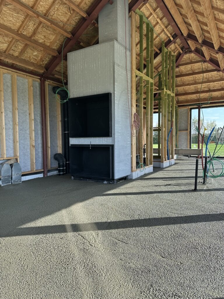 Chape en cours de construction à Hooglede : chape fraîche sur le sol, charpente en bois et cheminée en phase gros œuvre