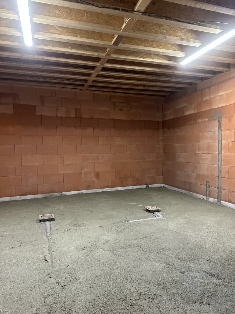 Toiture dans un nouvel espace de construction à Kluisbergen avec plancher en béton apparent, raccordements d'égouts, blocs de terre cuite muraux